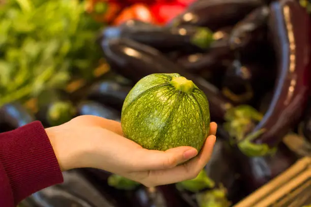 Photo of Female hand choosing ground zucchini in the store. Concept of healthy food, bio, vegetarian, diet.