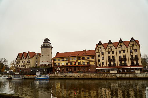 Kaliningrad, Russia November 15, 2019 City lighthouse among buildings from the side of the river. Observation deck house on the shore of the reservoir. The architecture of old houses.