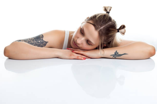 Portrait of a beautiful young tattooed woman, studio shot in front of white background