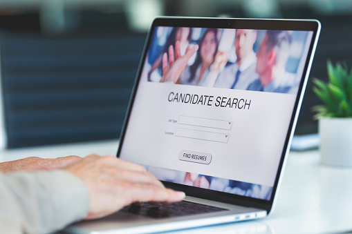 Businessman looking at recruitment website on a laptop computer. Candidate search page with job type and location buttons