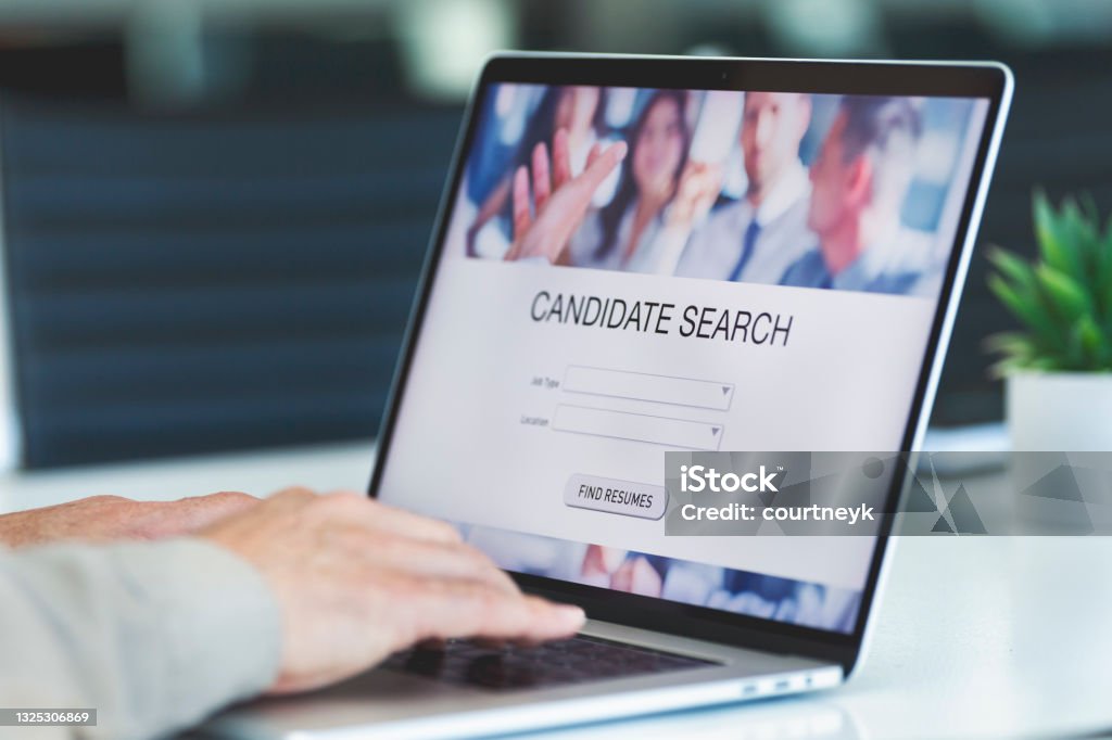Businessman looking at recruitment website on a laptop computer. Businessman looking at recruitment website on a laptop computer. Candidate search page with job type and location buttons Help Wanted Sign Stock Photo
