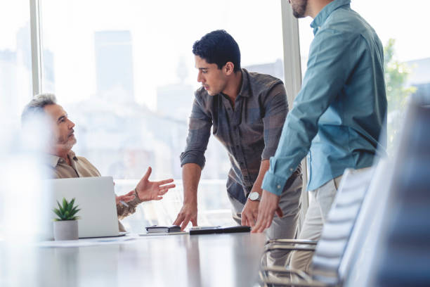 istock Three businessmen working and talking in a board room. 1325306871