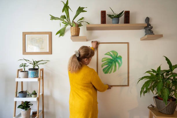femme âgée de race blanche décorant sa maison avec un nouveau tableau - home decorating photos photos et images de collection