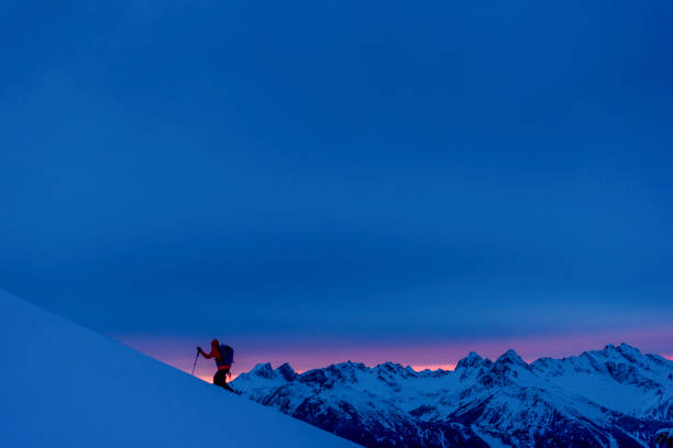 Backcountry skier climbs snow slope at sunrise Sun rises over distant Canadian Rockies extreme skiing stock pictures, royalty-free photos & images