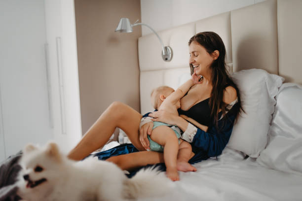 istock mother breastfeeding baby in bed with a dog 1325328197