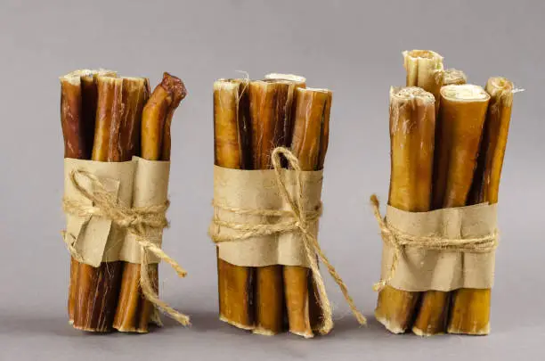 Photo of Bully sticks for dogs wrapped in brown paper and tied with twine. Portioned grouped Beef pizzle for pets. Air-dried 6-Inch Regular Bully Sticks