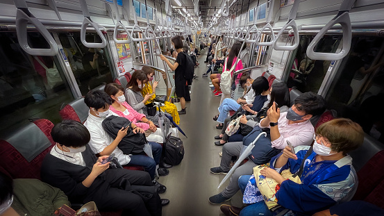 Tokyo, Tokyo Metropolis, Japan - June 19, 2021: Commuters on their cell phones during their evening ride through the city.