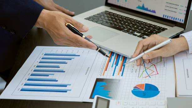 istock Businesswomen and men reading financial reports, discussing, analyzing, calculating graph documents that Asian female and male managers discuss and scrutinizing negotiation decisions. work as a team at work 1325334094