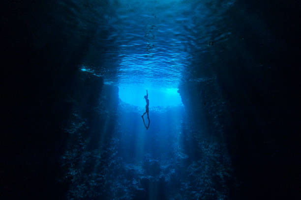 taucher schwimmen in unterwasserhöhle in richtung des lichts an der meeresoberfläche - hechten stock-fotos und bilder