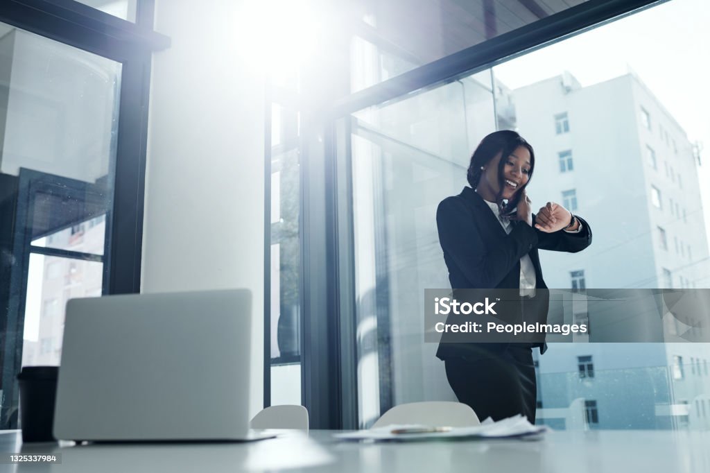 Shot of a young businesswoman using a smartphone and checking the time in a modern office Let your talent do the talking Checking the Time Stock Photo