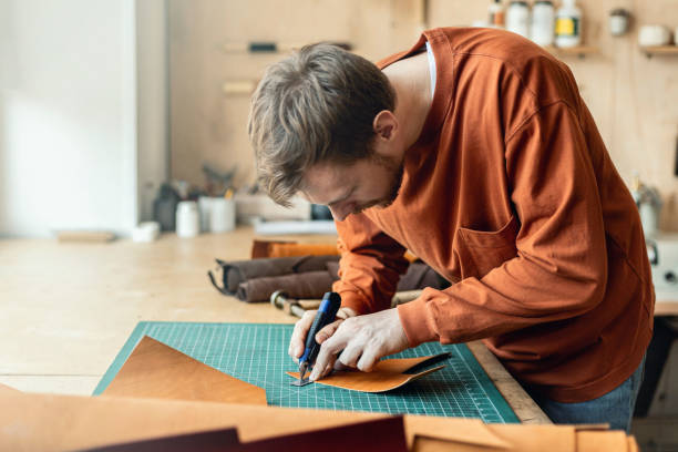 istock Male tanner making cutting scheme of bag working at leather workshop. Handcrafted creating 1325339482