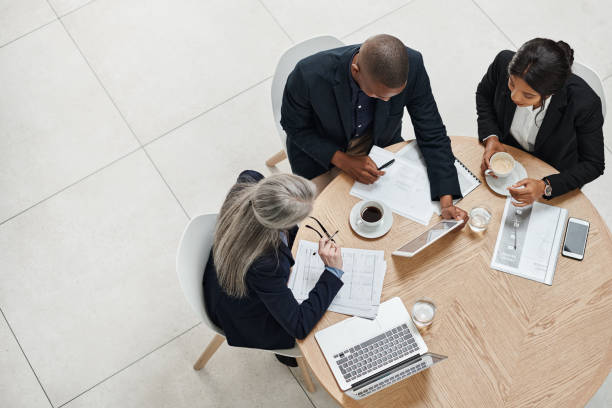 colpo ad alto angolo di un gruppo di uomini d'affari che si incontrano in un ufficio moderno - meeting document working people foto e immagini stock