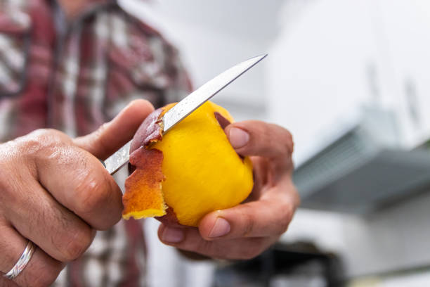 istock Man peeling a peach with a knife seen up close 1325345806