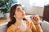 woman using cotton swab while doing coronavirus PCR test at home. Woman using coronavirus rapid diagnostic test. Young woman at home using a nasal swab for COVID-19.