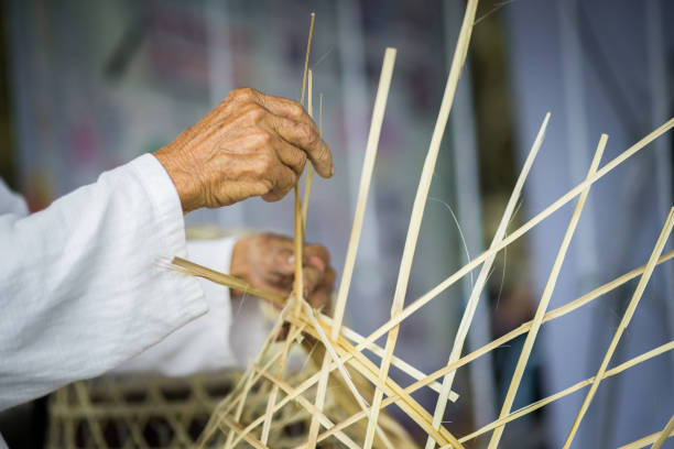 An old man is using his hands to weave a bamboo basket. It's a career that old people can do. An old man's hand is using a bamboo basket. It's a career that old people can do. It is a career promotion for old people to have jobs. bamboo fabric stock pictures, royalty-free photos & images