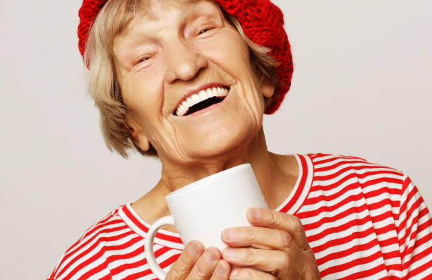 istock old excited lady smiling laughing, holding cup drinking coffee 1325353616