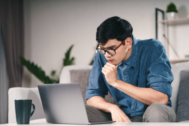 istock Pensive Thoughtful Serious Asian man in eyeglasses looking at laptop screen thinking for solution to solve the problem. 1325353867