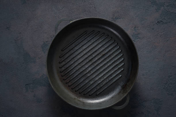istock Old dirty round cast iron grill pan on dark background top view 1325354725