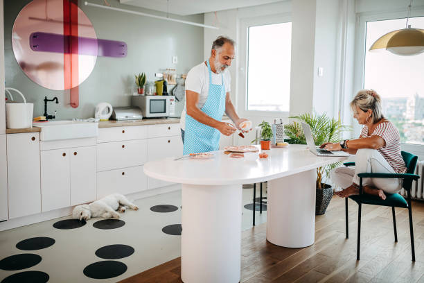 Senior man preparing food while wife is working