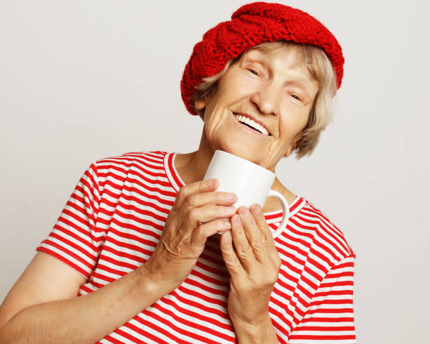 istock old excited lady smiling laughing, holding cup drinking coffee or tea 1325358834