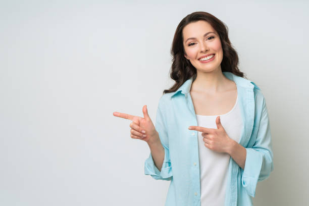istock Young woman smiling and gesturing to copy space 1325362308
