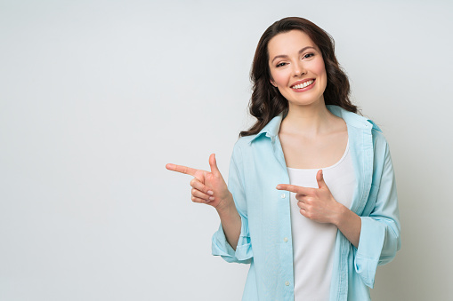 Young woman smiling and gesturing to copy space