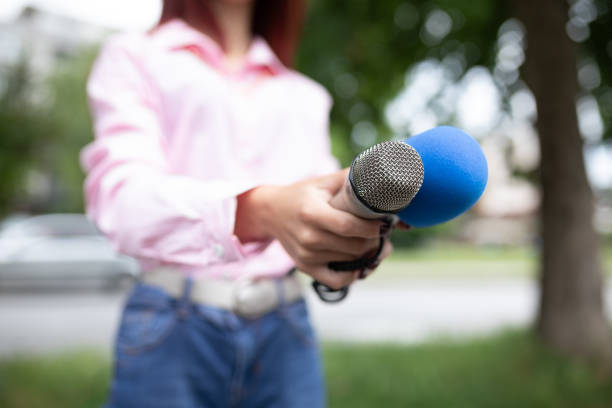 istock What is your storry? Journalist at news conference, writing notes, holding microphones 1325366553