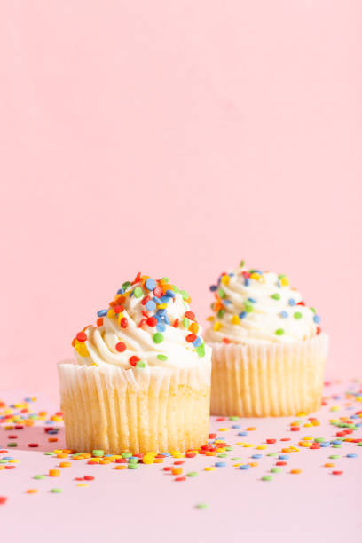 White cream cupcake with color sprinkles on rose White cream cupcake with color sprinkles on rose. High quality photo white wedding cake red roses stock pictures, royalty-free photos & images