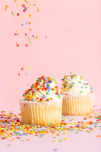 White cream cupcake with color sprinkles on rose. High quality photo