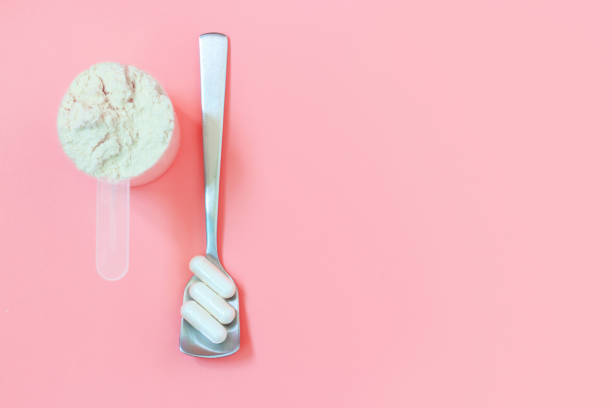istock Protein scoop and capsules on pink background close up, copy space 1325369053
