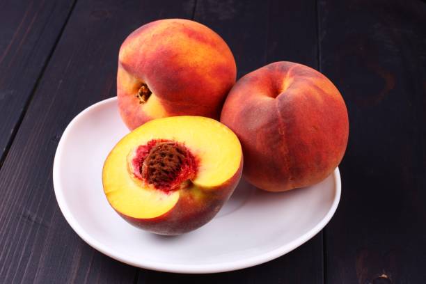 istock Peach in a plate on a dark wooden background 1325370151