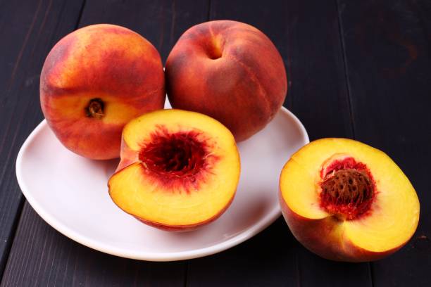 istock Peach in a plate on a dark wooden background 1325370509