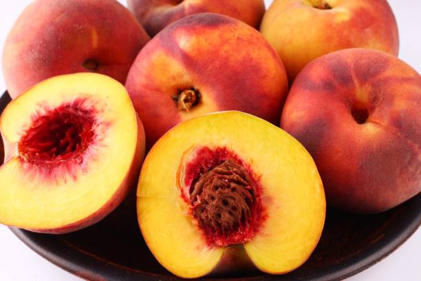 istock Peach in a plate on a dark white background close up 1325371042