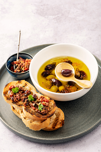 Homemade tapenade made from; black and green olives, fresh parsley, capers, olive oil, garlic sun dried tomatoes and lemon juice served on toasted french bread. Colour, vertical format with some copy space.
