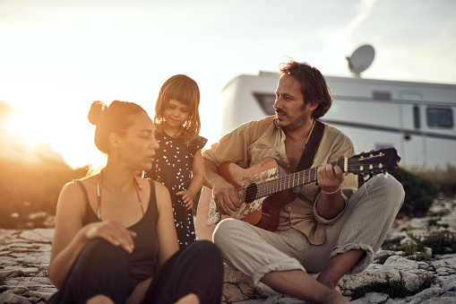 Family on a vacation, singing, playing music on a guitar and enjoying summertime vibes.