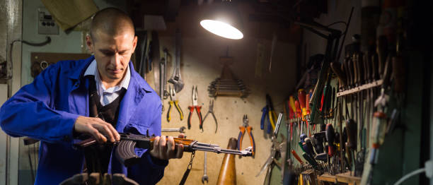 istock Gun repairman assembling Kalashnikov rifle after repair in workshop 1325384283