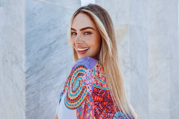 Young beautiful blond woman smiling outdoors in summertime Closeup portrait of young beautiful blond woman in summertime. Female outdoors wearing colorfull smock with marble column background fashion and beauty stock pictures, royalty-free photos & images