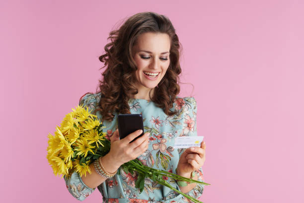 glückliche elegante frau mit smartphone-anwendungen auf rosa - single flower flash stock-fotos und bilder