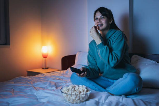 istock Woman having fun watching TV in bed at night 1325385821