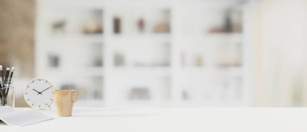 istock White working table with stationery, clock, cup and copy space in blurred background, 3D render 1325386235