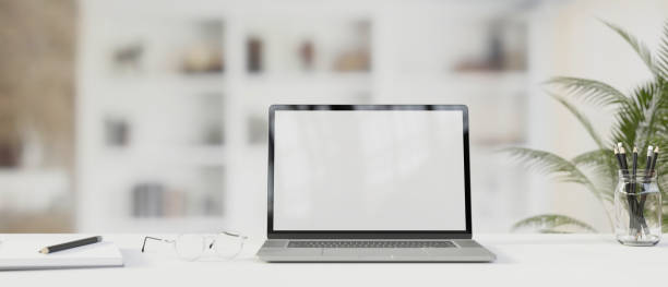 istock Laptop with mock-up screen on the table with stationery and eyeglasses with blurred background, 3D render 1325386256