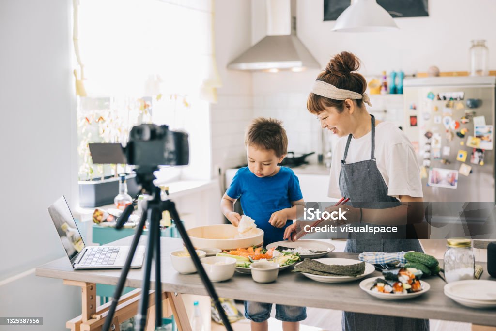 Mother and son recording cooking tutorial Japanese food blogger filming a tutorial with her son. Sushi Stock Photo