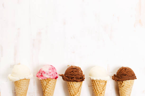 istock Ice cream scoops in cones on white wooden background. 1325387655