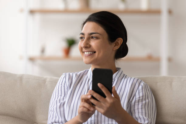 istock Smiling Indian woman use smartphone relaxing at home 1325391005