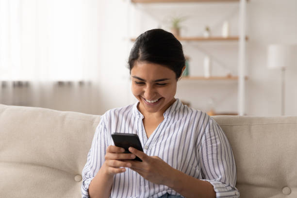 istock Smiling Indian woman relax at home using smartphone 1325391007