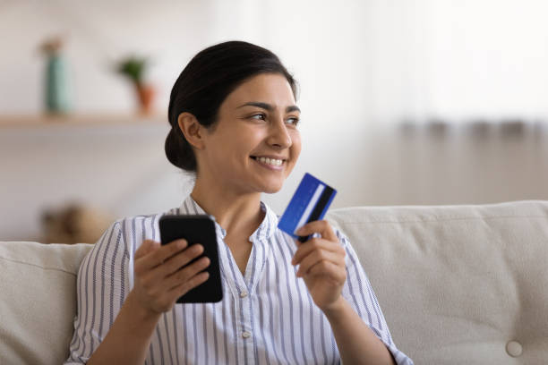 istock Smiling Indian woman make online payment on cell 1325391011