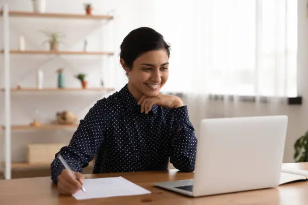 Photo of Smiling Indian woman study on computer at home
