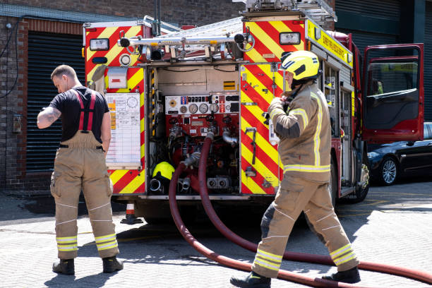 camión de bomberos y bomberos que asisten a un incendio en un aparcamiento público - uk fire department fire engine team fotografías e imágenes de stock