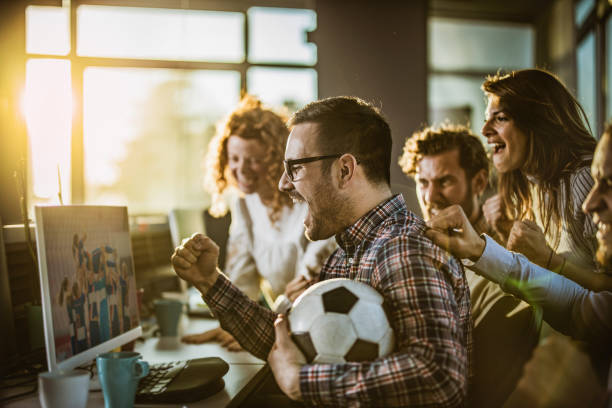 programadores alegres torcendo enquanto assistem sua equipe de esportes no pc no escritório. - office fan - fotografias e filmes do acervo