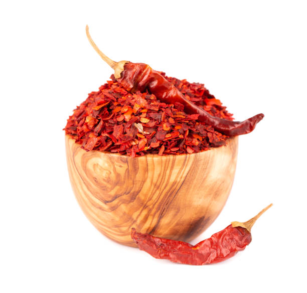 istock Dried red chili flakes in olive bowl, isolated on white background. Chopped chilli cayenne pepper. Spices and herbs. 1325395966